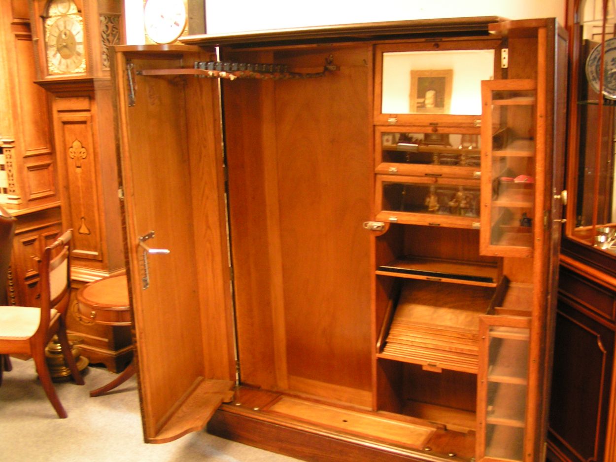 Verkocht 1600240 The Gentlemans Compacton - London: 
This piece of furniture is a mystery object. On the outside it looks very ordinary but on the inside it\'s like Aladdin\'s cave.
This Gentleman\'s Compactom resides at Bedervale, a historic home in Braidwood, NSW. The contents of Bedervale is from two families: six generations of the Cogal-Madrel family and the Royds family who moved here in 1973. All the contents that were owned by the Cogal-Madrel family are now owned by the National Trust, gifted by a grant from the National Estate. Bedervale is a living museum.
Victoria, accompanied by her mother Margaret Royds, took me on a tour of the house, sharing with me a few secrets of various objects at Bedervale.
The first object is a Gentleman\'s Compactom.
The Compactom wardrobe - also known as chiffarobe, chifferobe, wardrobe, armoire, dresserobe, closet and Gentleman\'s Butler - demonstrates how an object reflects upon the society that used it. Produced from the 1920s to the 1950s it illustrates how \'designers used wardrobe space to offer the supposed benefits of a tidy and orderly life in a period of rapid change\'. The wardrobe identifies a number of issues including concerns about efficiency, loss of domestic staff, clothes maintenance and middle-class identity\'. Viewed within the context of Bedervale you can see how apparent this was.
During the 1920s Compactoms were often acquired into the marriage when newlyweds started a home together. They were commonly sold as sets with the rest of the bedroom furniture, but could also be purchased individually.
Description:
The moulded cornice above a pair of panelled doors enclosing a well-fitted interior of hooks to the right and shelves and compartments to the left, some with glazed doors and others open, bearing labels reading \'Opera Hats\', \'Pyjamas\' and \'Dress Shirts\' etc., the doors with rails and further shelves, with a lidded compartment for \'Sundries\' in the plinth, 127cm wide x 56cm deep x 174cm high, (50\" wide x 22\" deep x 68.5\" high)
A gentleman\'s mahogany Compactom wardrobe, early 20th Century bearing label to interior reading \'Compactum...41 - 44 Upper Berkely St. London\' and retailer\'s label for \'Finnigans Ltd.\'
Keywords: The Gentlemans Compacton